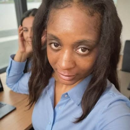 Black woman with long dark hair in a blue shirt looks directly at the camera.